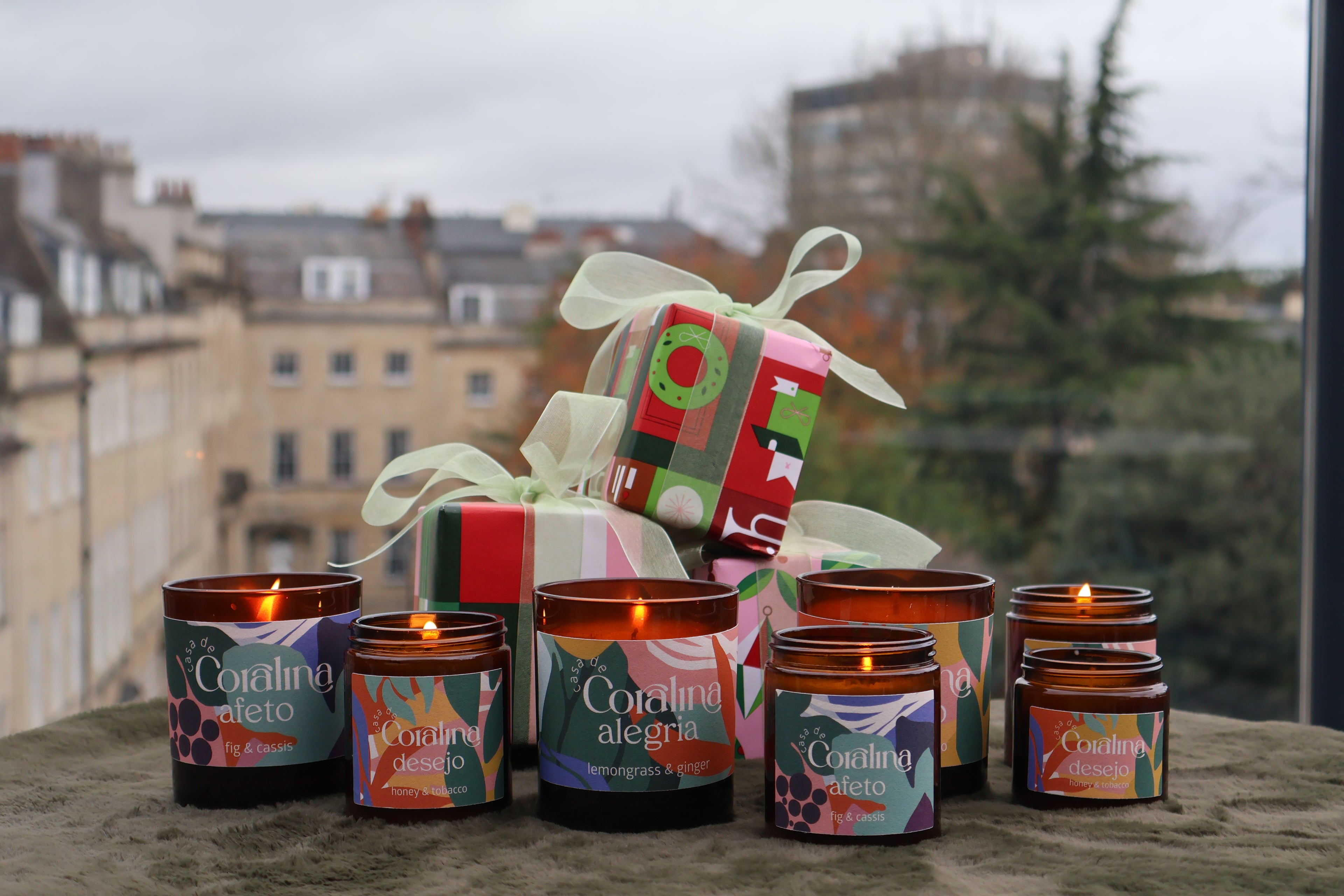 Set of colorful candles with decorative packaging on a surface with a cityscape background