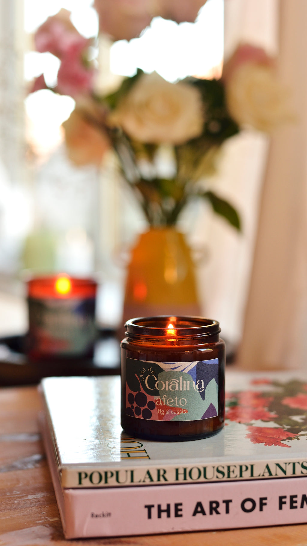 Candle in an amber jar on a stack of books with a blurred background