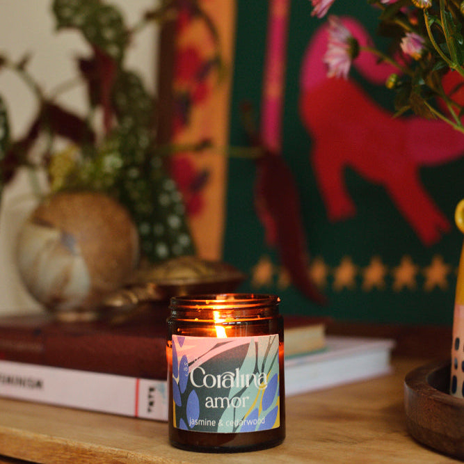 Candle labeled 'Corail amar' on a wooden surface with decorative items in the background