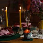 Dinner table setting with candles, wine glasses, and flowers in a dimly lit room.
